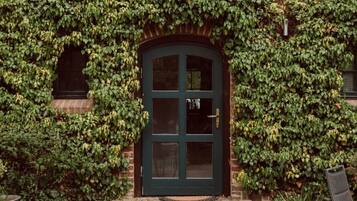 Un bâtiment en briques avec une porte verte et des murs couverts de lierre.