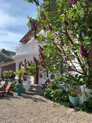 A building with a white facade, a balcony, and a gravel courtyard with potted plants and outdoor seating. - Chambres d'hôtes Villa Mon Repos (Saint-Aubin-sur-Scie)