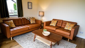 Un salon avec deux canapés en cuir marron, une table basse en bois et une lampe.
