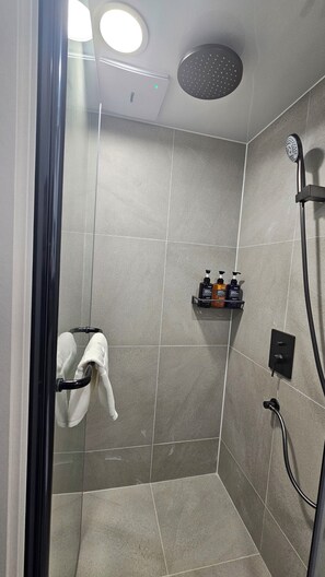 Una ducha moderna con cabezal de ducha manual, puerta de cristal y un perchero para toallas.