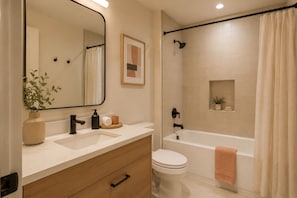 Ein Badezimmer mit Waschbecken, Spiegel, Toilette und Badewanne.