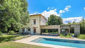 Ein modernes Haus mit Swimmingpool, Steinmauern und einem Garten.
