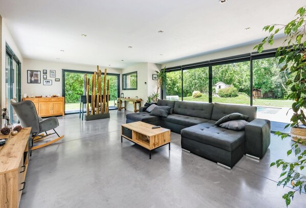 A modern living room with a sectional sofa, a wooden coffee table, and a dining area with a wooden cabinet and chairs. - House in Bouyssou - Nature and Elegant (Viterbe)