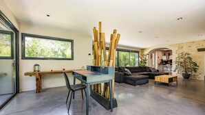 Ein zeitgemäßer Wohnraum mit Schreibtisch, Stuhl, Sofa und einem großen Fenster.