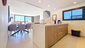 Una cocina moderna con una isla central, comedor con sillas y un ventanal grande.