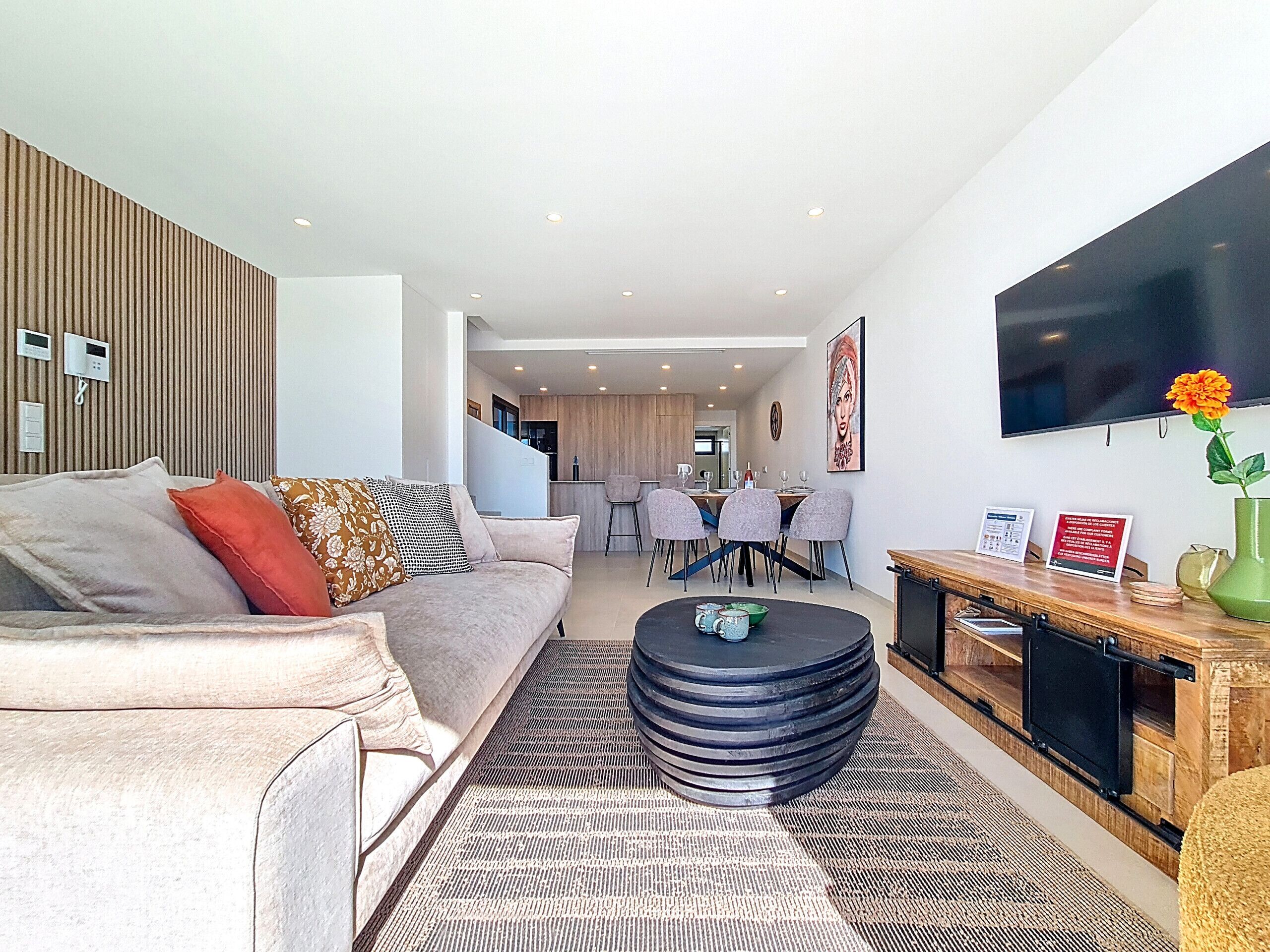 A modern living room with a sofa, coffee table, and a TV mounted on the wall.