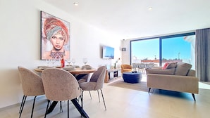 Una sala moderna con comedor, ventanas amplias y vista a la ciudad.
