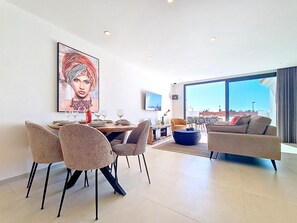 A modern living room with a dining area, large windows, and a city view. - Penthouse | Private Terrace & Pool Views (Los Alcazares)