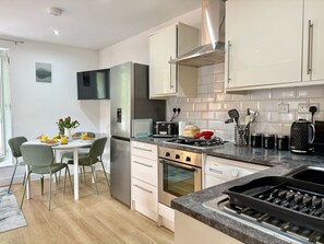 Een moderne keuken met een eethoek, roestvrijstalen apparatuur en een betegelde spatwand.