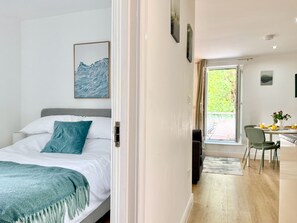 Ein Schlafzimmer mit Bett, Fenster und Blick auf den Essbereich.