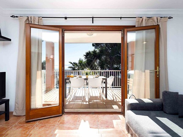 A room with a sliding glass door leading to an outdoor patio with a table and chairs. - Chalet Mirador in Alcudia - Puerto de Alcudia (Alcúdia)