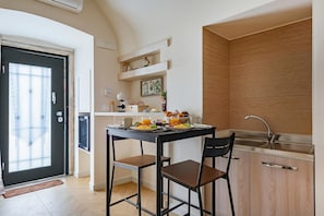 Uma cozinha compacta com área de jantar, pia e porta que dá para uma varanda.