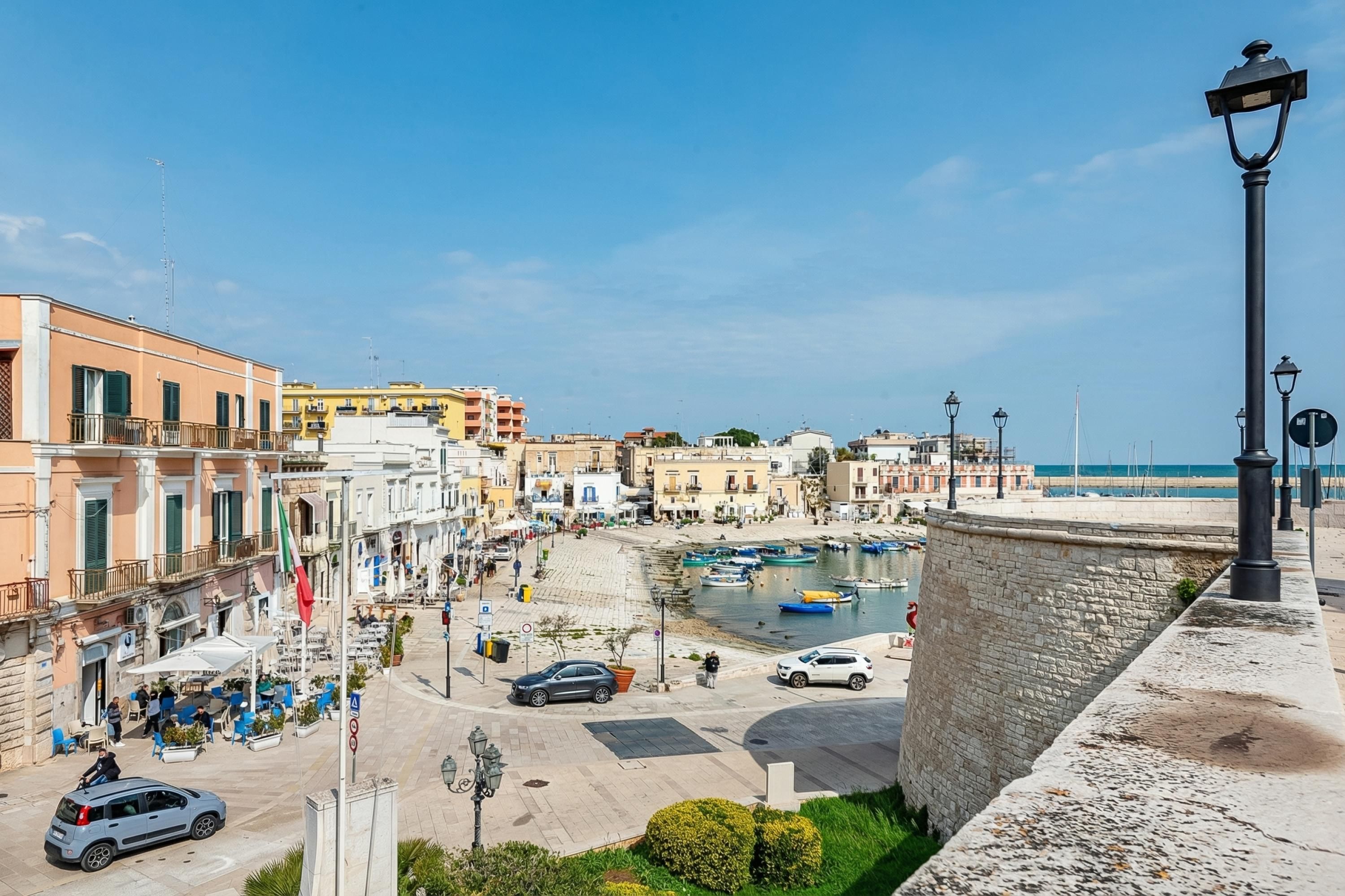 A coastal town with historic buildings, a marina, and a stone wall.