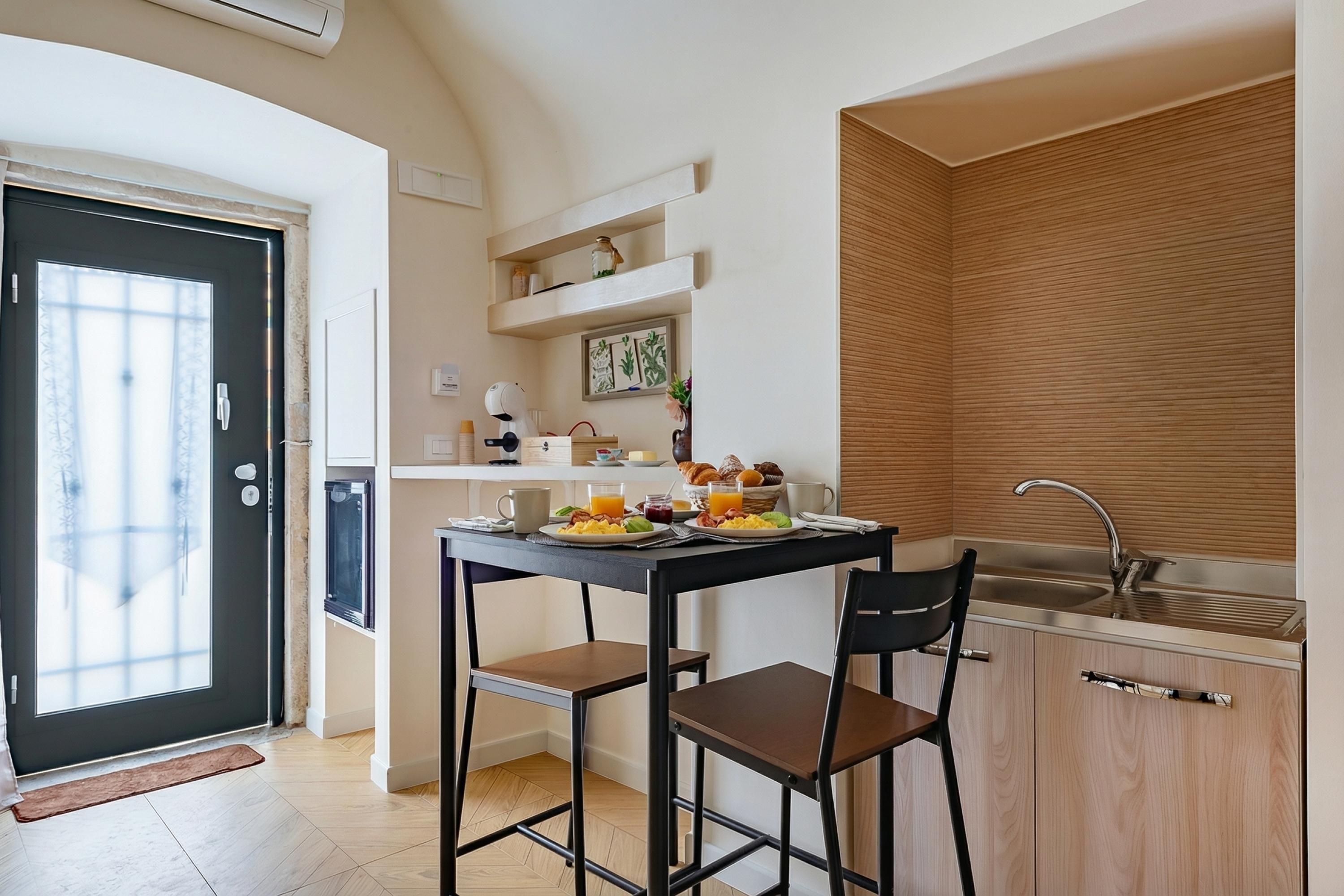 Une cuisine compacte comprenant un coin repas, un évier et une porte donnant sur un balcon.