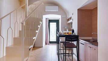 A modern kitchen with a dining area, a staircase, and an open door leading to another room.