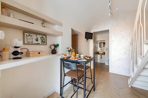 A modern kitchen with a dining area, a coffee machine, and a TV mounted on the wall. - La Chicca Sul Mare Sea View (Bisceglie)