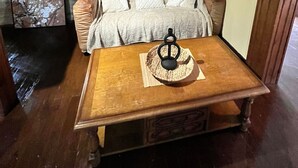 Una habitación acogedora con una mesa de madera, un banco acolchado, una pared de piedra y un cuadro enmarcado.