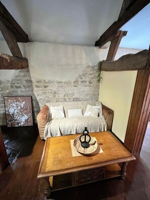 Een gezellige kamer met een houten tafel, een beklede bank, een stenen muur en een ingelijste foto.