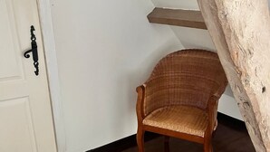 Una habitación con una silla de madera, un tapete tejido y una puerta blanca con picaporte negro.