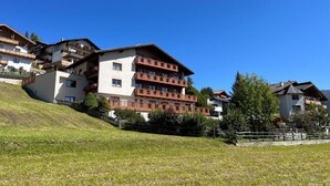 Un edifici d'edificis amb balcons, ubicat en una pendent coberta d'herba.