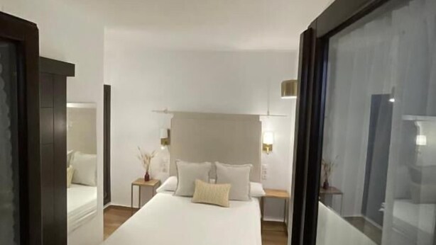 Una camera da letto con un letto grande, un comodino, una sedia e un pannello di vetro.