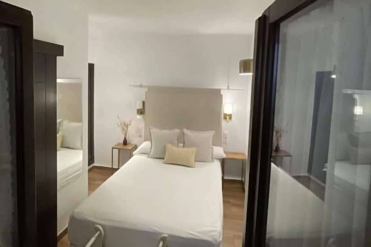 Un dormitorio con una cama grande, una mesita de noche, una silla y un separador de vidrio.