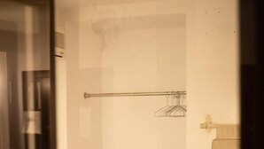 Una camera d'albergo con un letto, un tavolino con un vaso, un portasciugamani e uno spazio doccia.