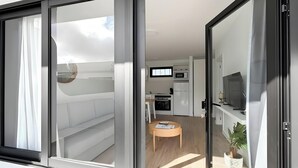 Un interno moderno con una porta scorrevole in vetro che dà su un balcone, una zona cottura con elettrodomestici e un piccolo tavolo rotondo con una pianta.