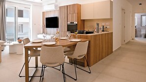 A modern kitchen with wooden cabinets, a central island, and a flat-screen TV. - Modern Seaside Apart in Marsalforn - 5E, Marsalforn Iz-Zebbug Gozo, Malta (Marsalforn Iz-Zebbug Gozo)