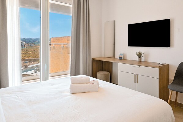 Une chambre d’hôtel avec un lit, un bureau, une télévision et une vue sur la ville.