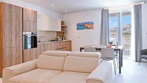 Et moderne køkken med indbyggede apparater, et spiseområde med bord og stole, samt et stort vindue med udsigt.