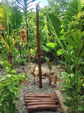 Un jardín con diversas plantas, una estructura de madera y un sendero de grava.