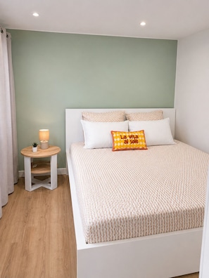 A neatly arranged bedroom with a bed, pillows, a bedside table with a lamp, and a small plant. - Chez Aurel et Ju (Tournon-sur-Rhône)