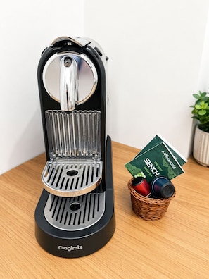 Een Nespresso koffieapparaat met een mand koffiecups en een groene doos Sencro groene thee.