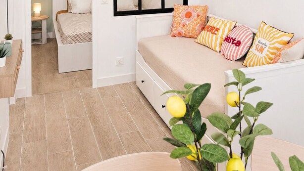 A modern bedroom with a bed, a sofa, a small table, and a potted plant. - Chez Aurel et Ju (Tournon-sur-Rhône)
