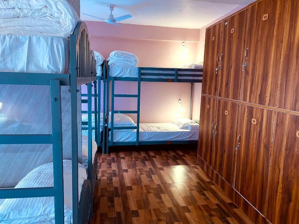 A bunk bed room with a wooden wardrobe and a ceiling fan.