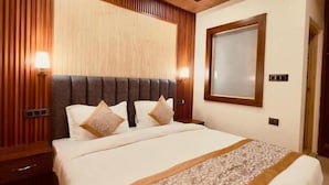 A hotel room with a wooden ceiling, a bed with a headboard, a bedside table, and a nightstand. - Milam Hostel (Leh)