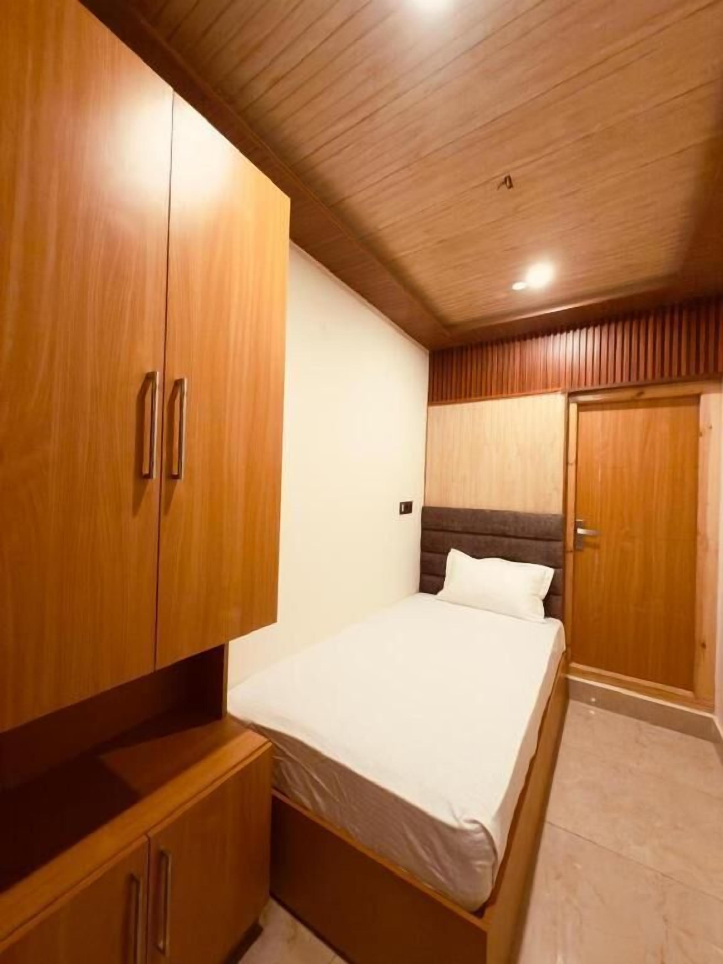 A bedroom with a bed, wooden wardrobe, and a door.