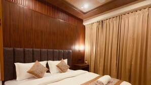 A hotel room with a large bed, wooden paneling, a ceiling fan, and curtains. - Milam Hostel (Leh)