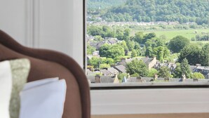 A room with a large window overlooking a town, a bed, and a lamp. - The Stirling Lookout | Panoramic Terrace Views | Steps from Stirling Castle (Stirling)