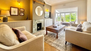 A living room with a fireplace, sofas, a coffee table, and a large window. - The Stirling Lookout | Panoramic Terrace Views | Steps from Stirling Castle (Stirling)