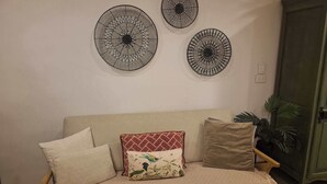 Ein beiges Sofa mit gemusterten Kissen, ein runder Wanddekor und ein grüner Schrank.