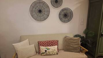 A beige sofa with patterned cushions, a wall-mounted circular decorative item, and a green cabinet.