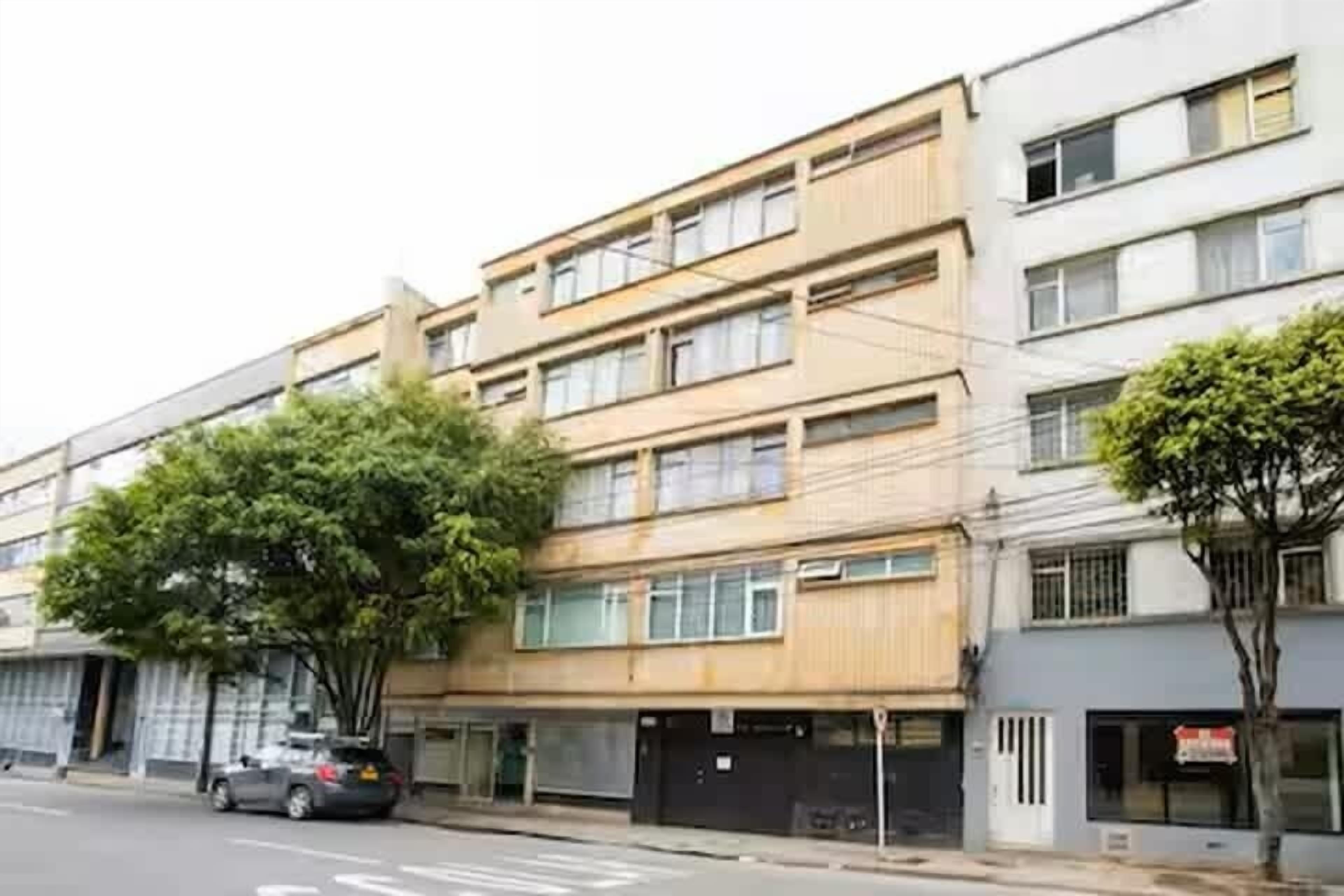 A multi-story building with a flat facade, large windows, and a tree in front.