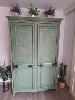Ein türkisblau gefärbter Schrank mit zwei Türen und einem kleinen Regal obenauf.