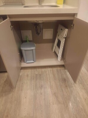 A kitchen with a built-in oven, a trash bin, and a cabinet under the sink. - Lourdes Executive Suites 204 (Bogotá)