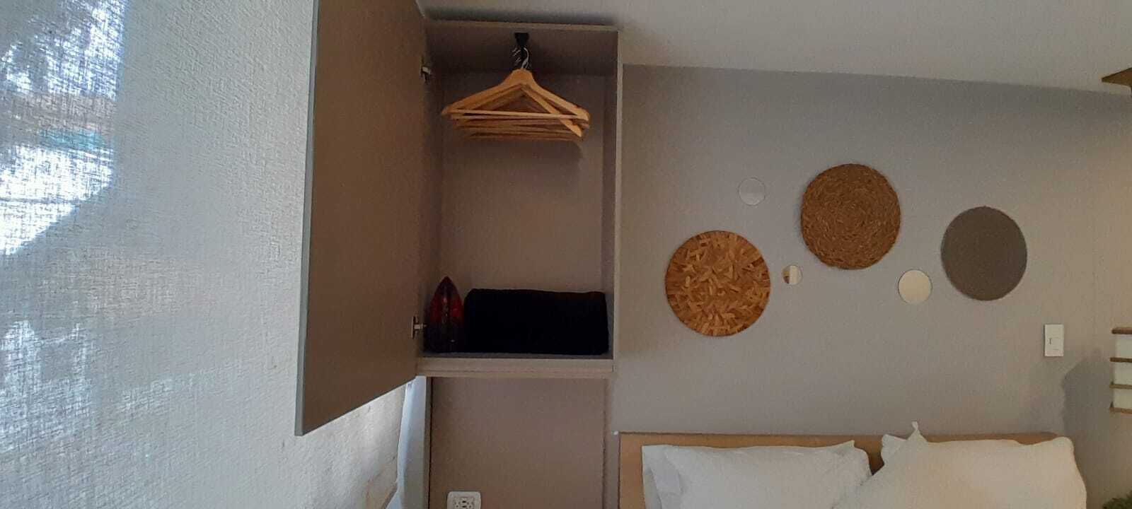A bedroom with a bed, a hanging rack, and three circular wall decorations.