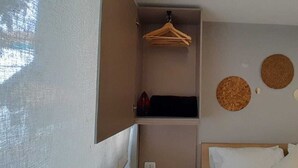 A bedroom with a bed, a hanging rack, and three circular wall decorations. - Lourdes Executive Suites 203 (Bogotá)