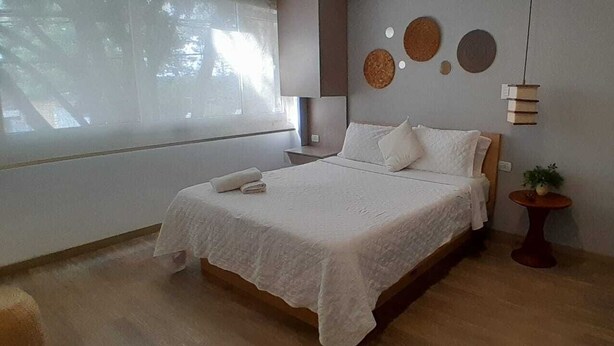 A bedroom with a bed, bedside table, and a small potted plant. - Lourdes Executive Suites 203 (Bogotá)