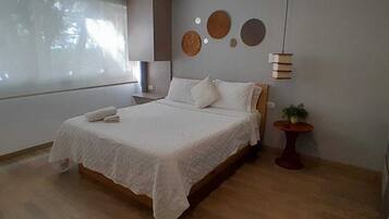 A bedroom with a bed, bedside table, and a small potted plant.